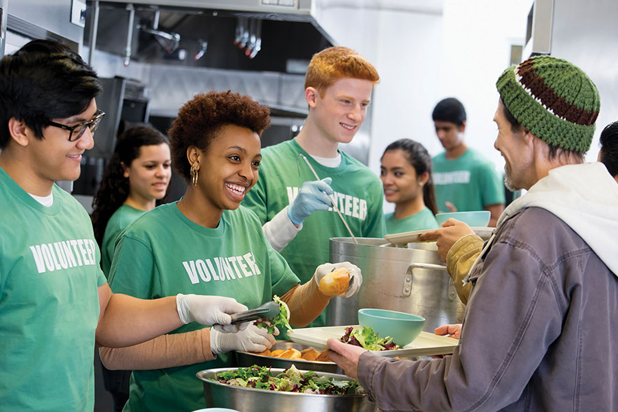 Volunteers in green shirts serving food to people.