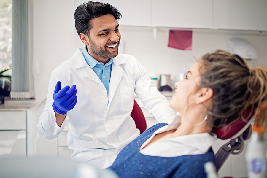  A man and a woman conversing in a dental chair during a dental appointment.