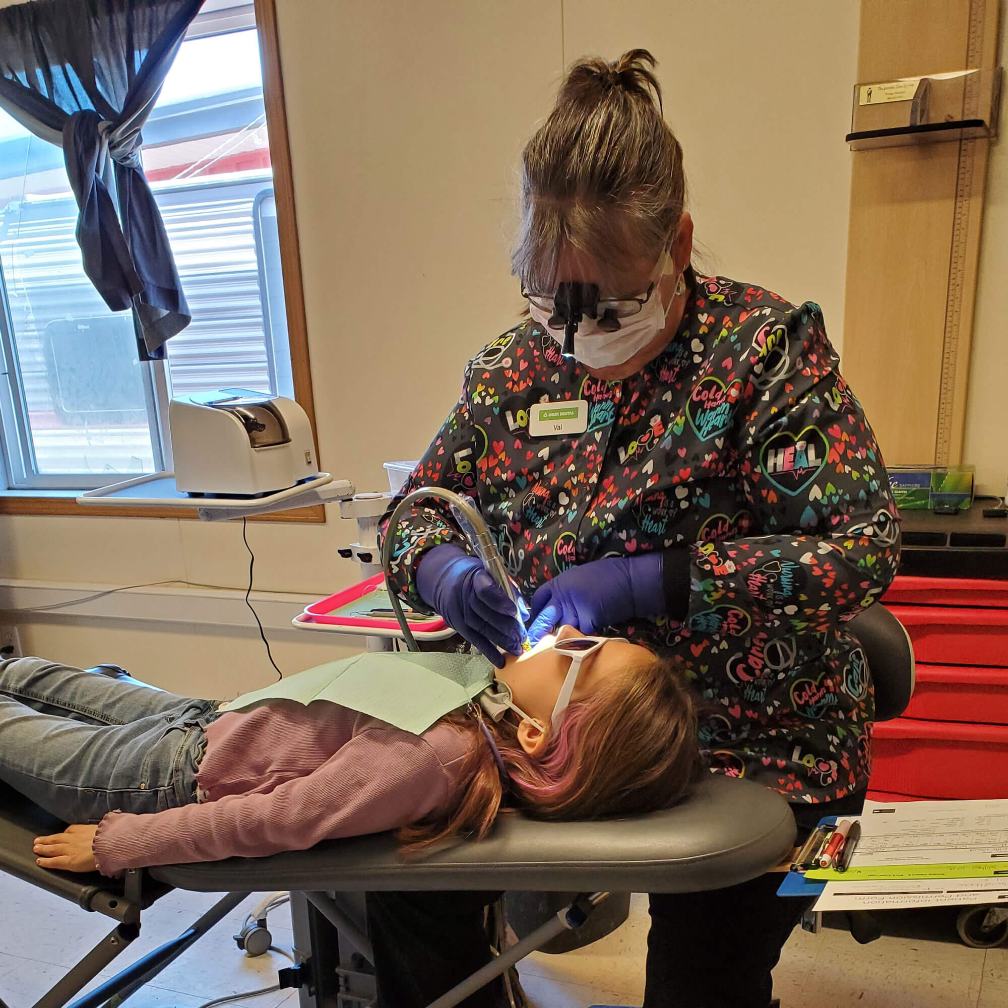 A child dentist examining a girl's teeth.